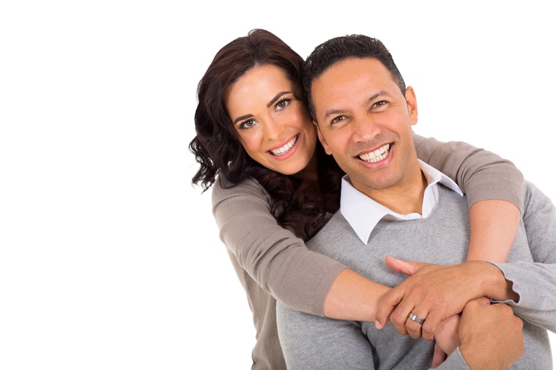 A couple cuddling while smiling at the camera