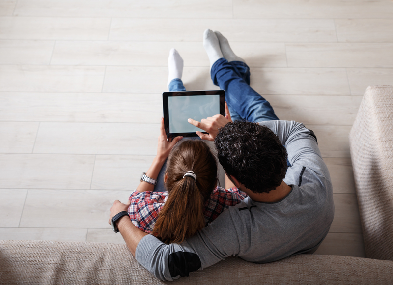 A couple looking at their tablet while sitting on the floor