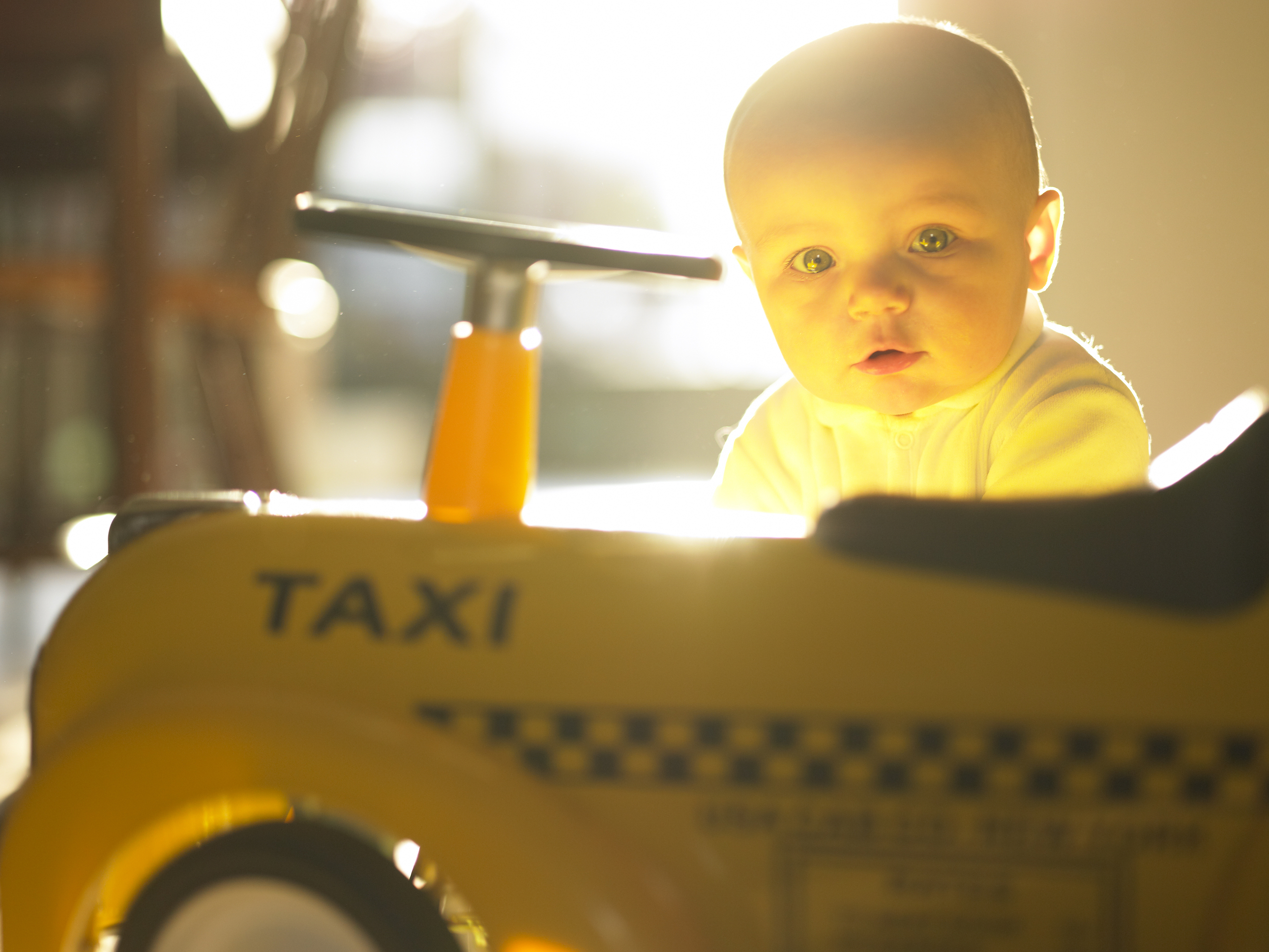 Baby sitting behind a miniature taxi