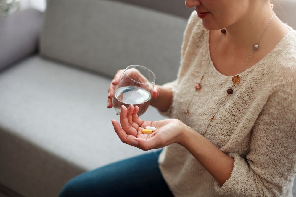 A female with fertility supplements and a glass of water