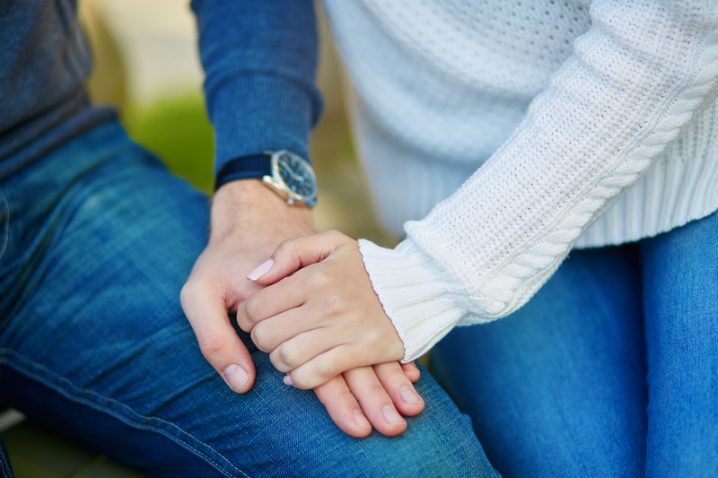 Close up of a male and female holding hands