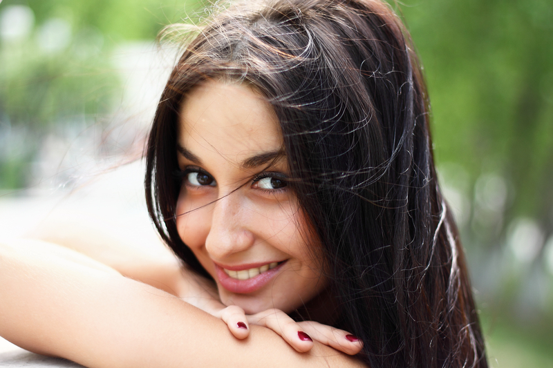 A female smiling at the camera as her hair blows in the wind
