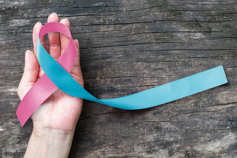 A hand holding a prematurity awareness ribbon
