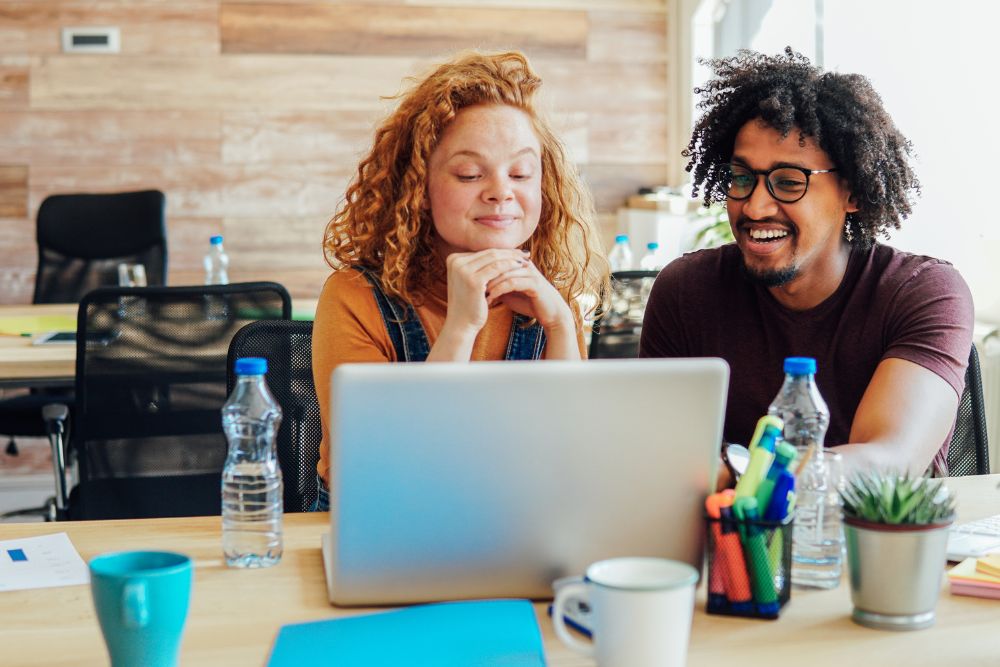 A couple in an office looking at their laptop