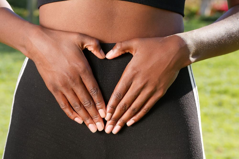 An African American female with her hands on her pelvis
