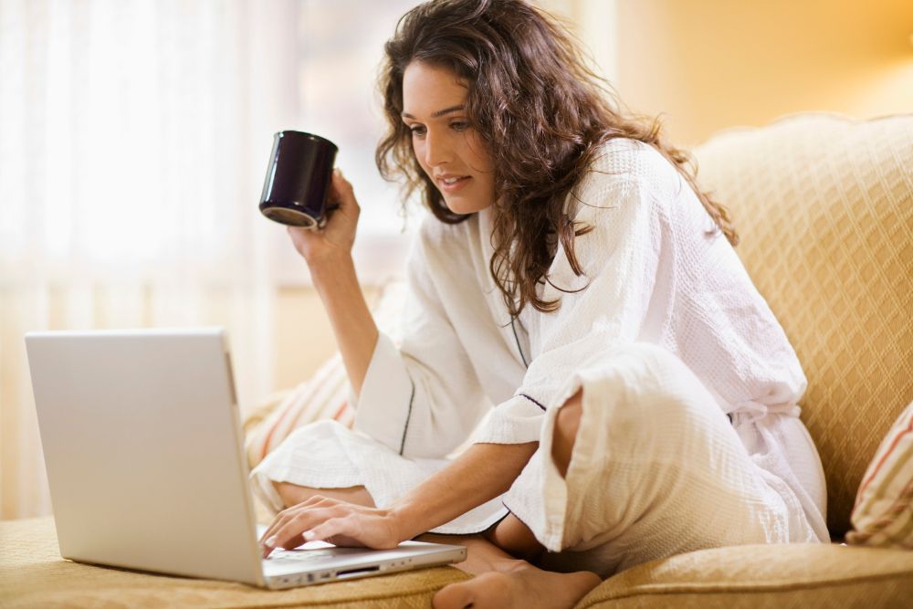 A female in her pajamas looking at a laptop