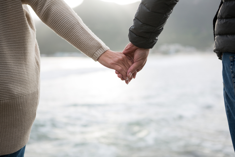 Two peope holding hands near a body of water