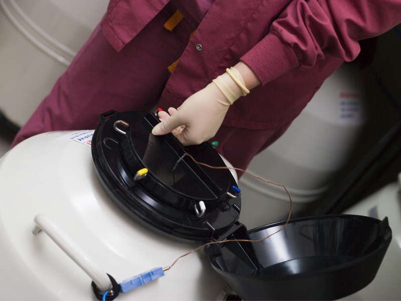 Embryologist opening a liquid nitrogen storage container
