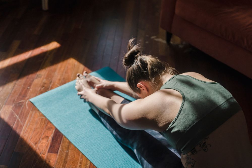 A female doing stretches on a blue yoga mat