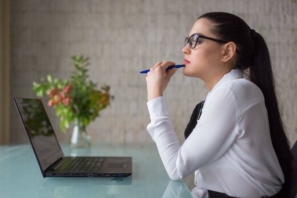 A female contemplating while holding a pen