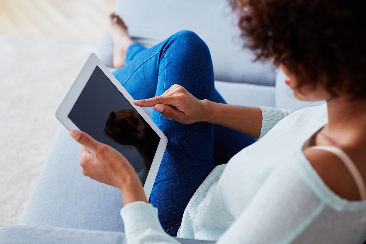 Female lying on the couth and scrolling through her tablet