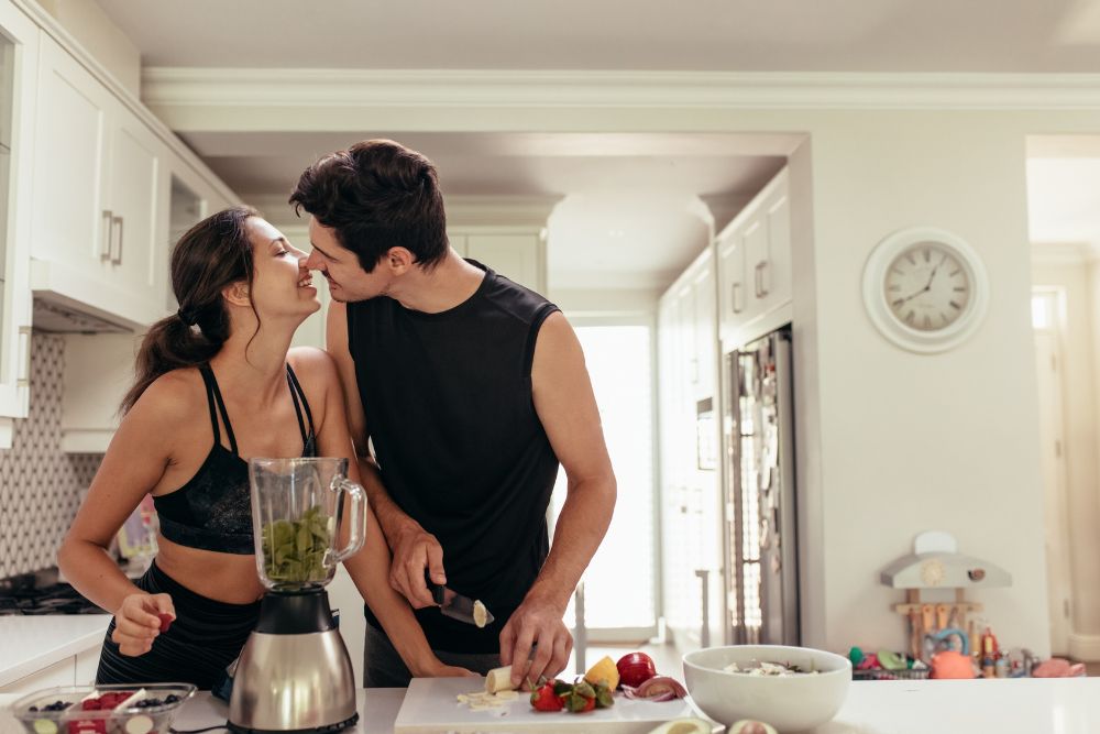 couple slicing fruit and kissing