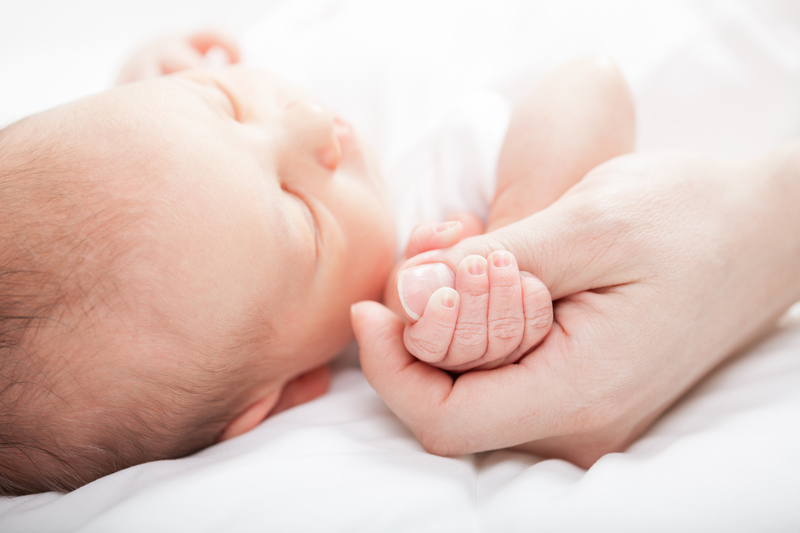 A person holding hands with a sleeping baby