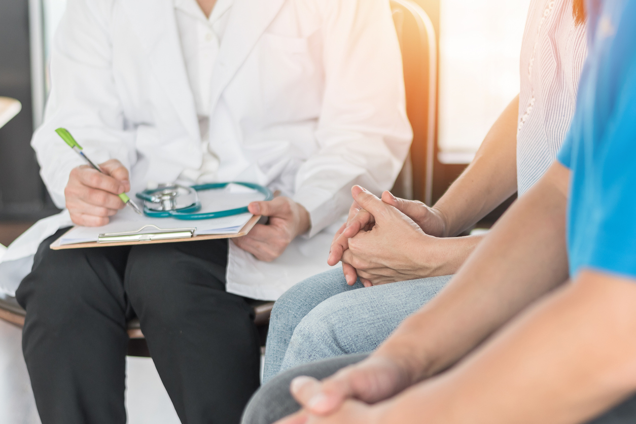 A couple waiting patiently while a fertility doctor records notes