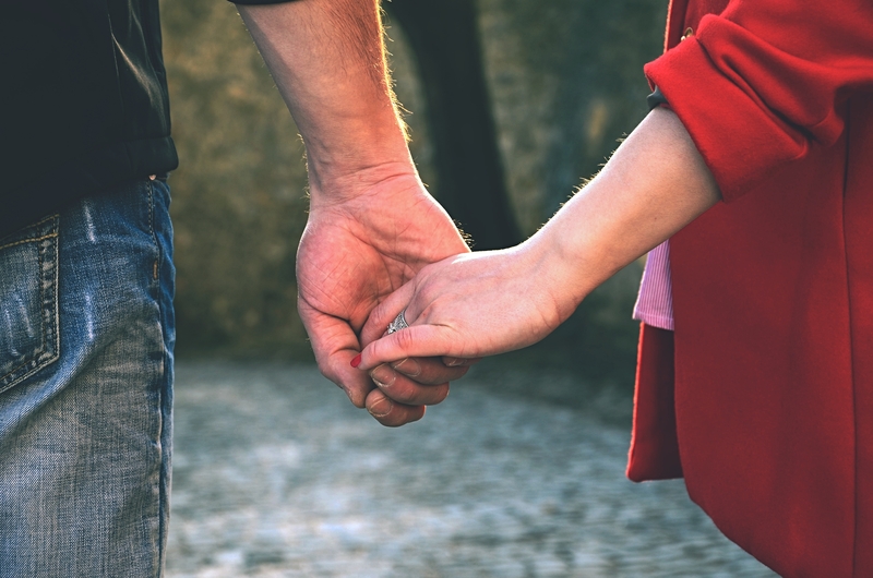 A male and female holding hands in a forest