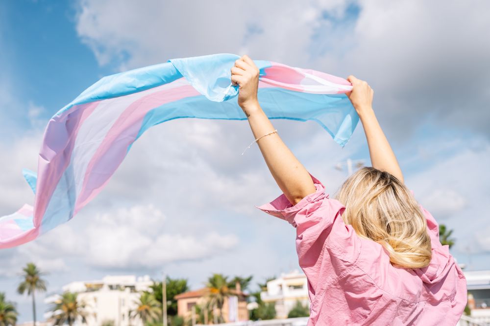 A female holding a trans pride flag